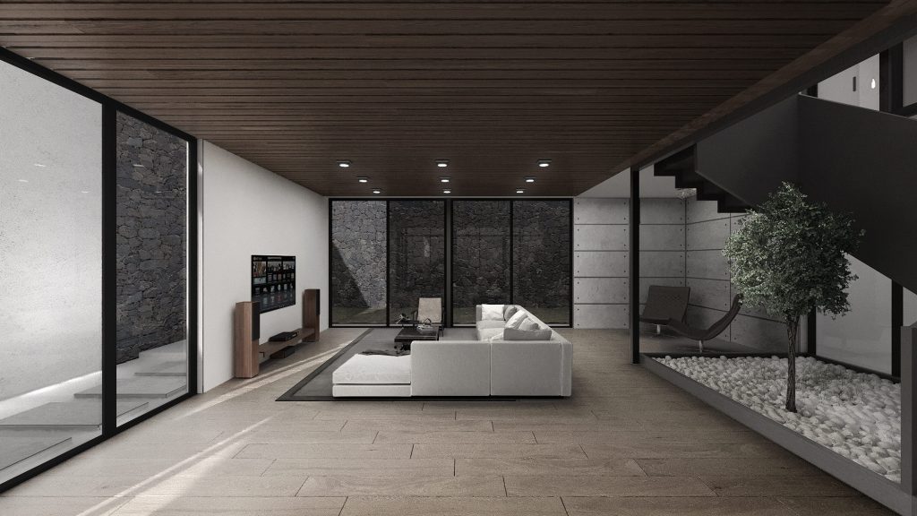 A living room with a white sofa, a dark wood ceiling, a stone wall and a small planted courtyard with a tree behind glass.
