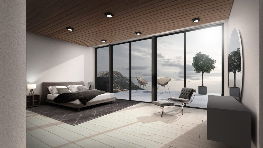 A bedroom with a dark bed, a lounge chair and floor-to-ceiling glass onto a terrace and the hills.