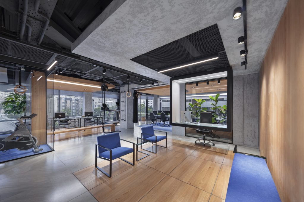 Lounge with blue armchairs in front of a framed meeting box and the training area.