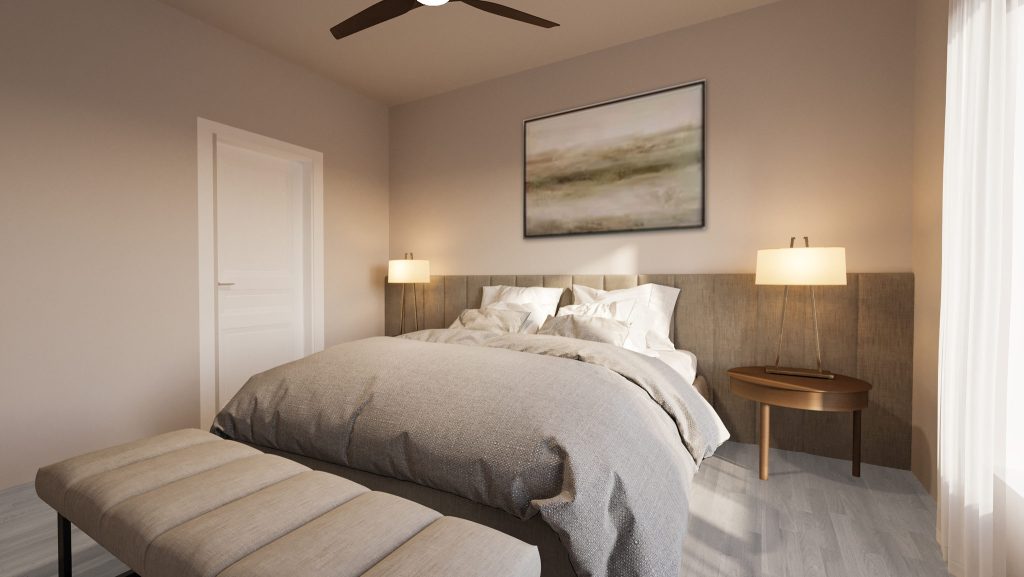 The model unit bedroom in soft neutrals, with a gray upholstered bed, bedside lamps, a landscape painting and a ceiling fan.