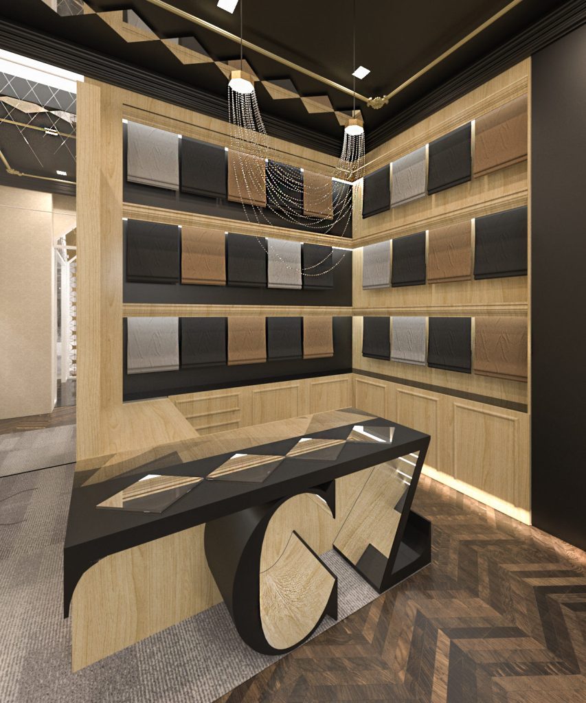 A wall of folded textiles in wood shelving above a black counter with a large gold monogram, on a herringbone floor.