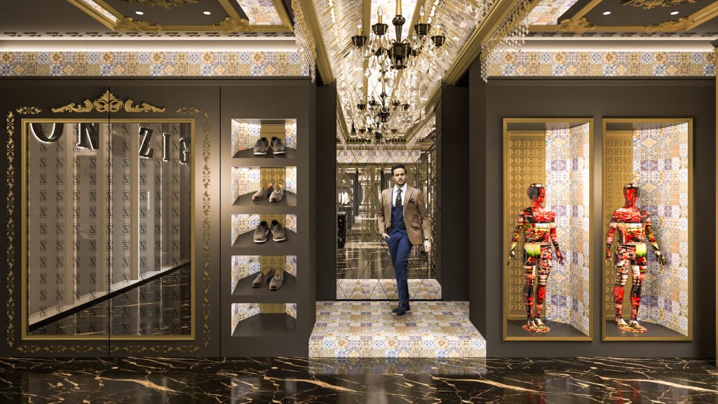 A tailoring corner with a man trying on a suit on a white plinth, framed patterned panels and a crystal chandelier.