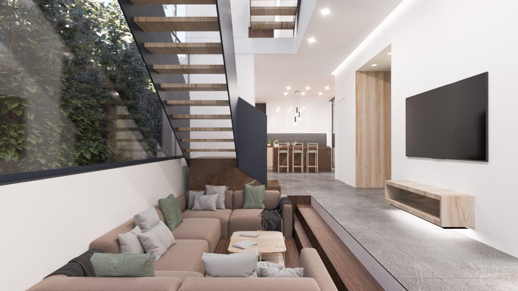 A living room with a wraparound beige sofa sunk into the floor, a floating timber stair, a TV wall and tall windows onto trees.