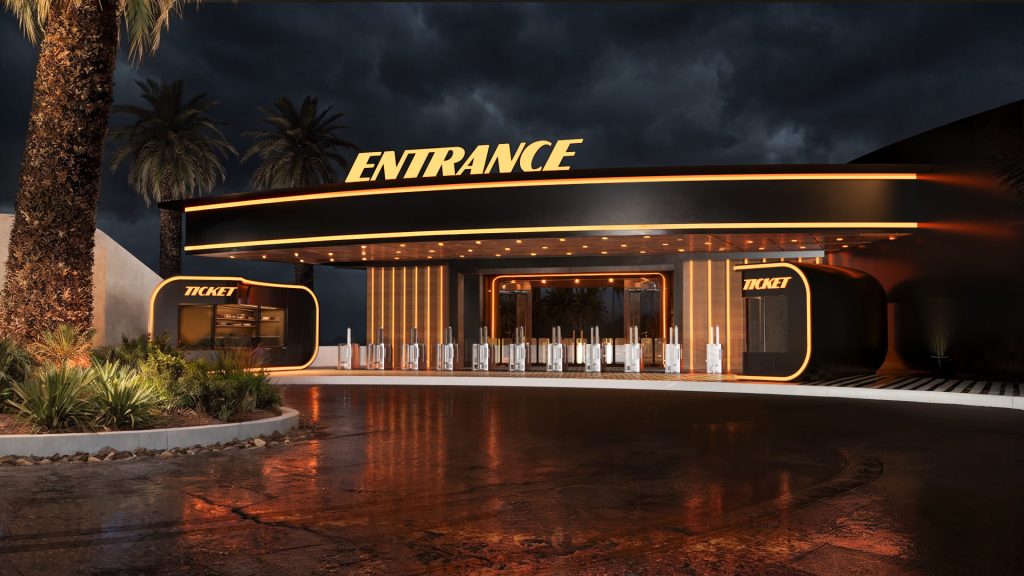 A long backlit entrance pavilion with ticket booths and a glowing entrance sign, framed by palm trees on a wet paved forecourt.