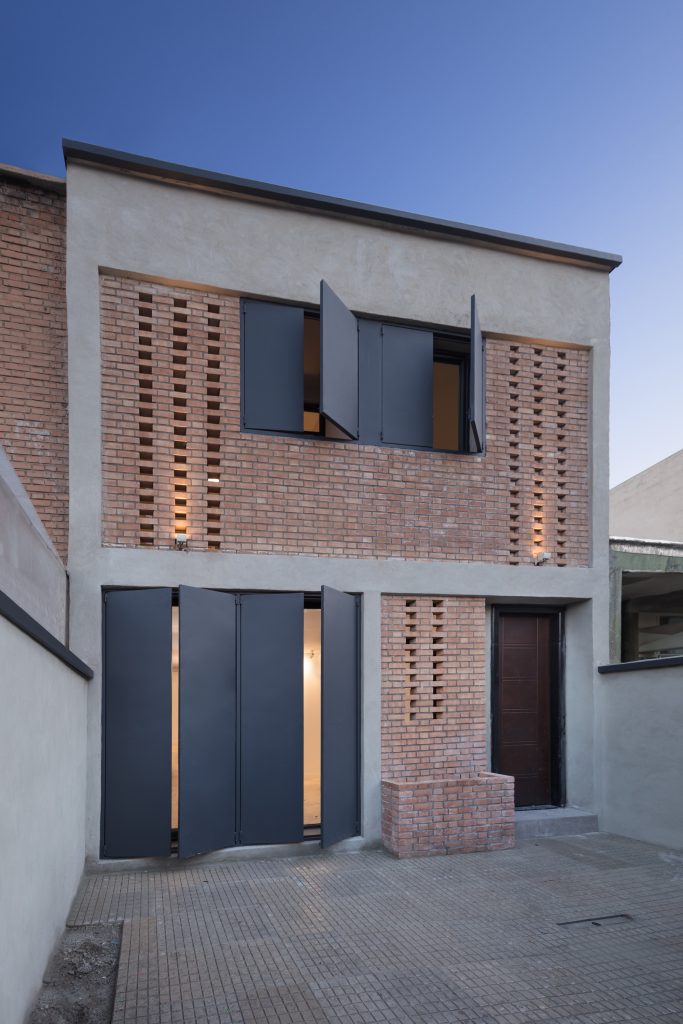 The front with its perforated brick screen and dark metal doors and shutters.