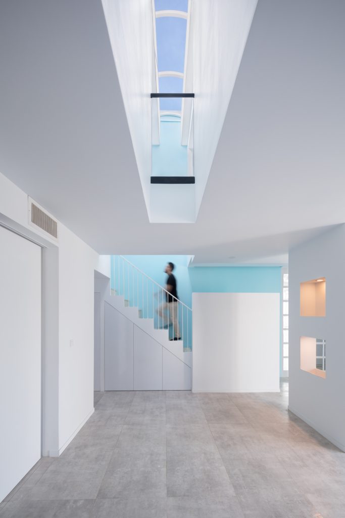 Stair hall with a long skylight, white walls and a sky-blue stair wall.