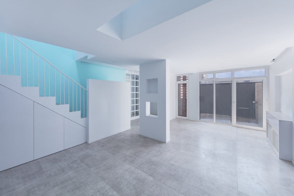 Ground floor living space with the blue stair, a concrete-look floor and glass doors.