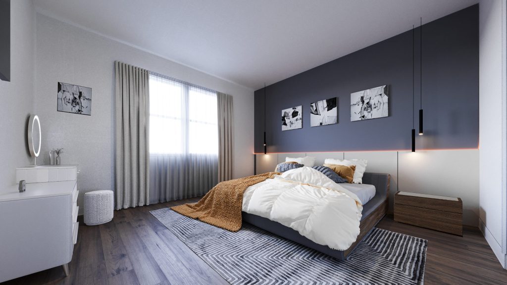 A bedroom with a dark navy accent wall, framed prints, slim pendant lights, textured bedding and a patterned rug.