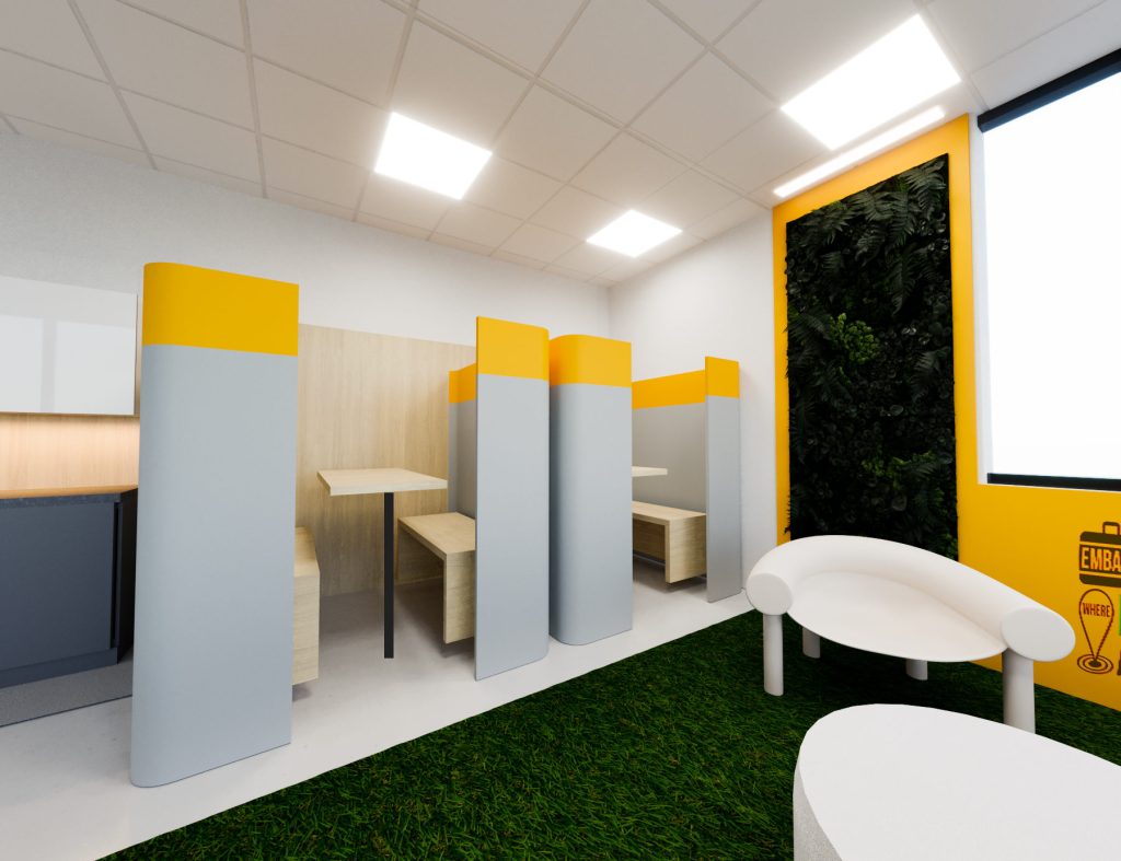 Gray booth partitions with yellow tops beside a grass-carpet lounge with white pod chairs and a living green wall.