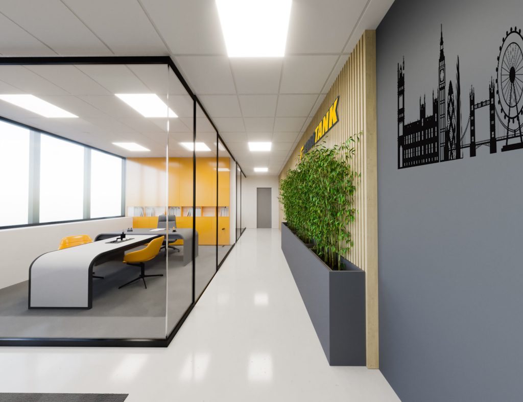 A corridor beside a glass-walled meeting room with a curved white desk and yellow chairs, a planter and a skyline graphic on a gray wall.