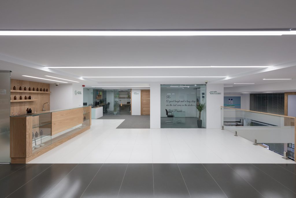The upper floor with a wood reception counter, glass offices and a polished dark floor band.
