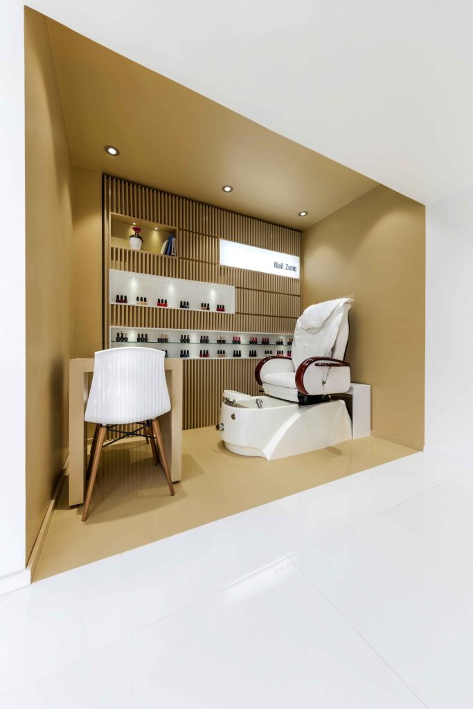 Pedicure chair in a golden niche with wood-slat shelving.