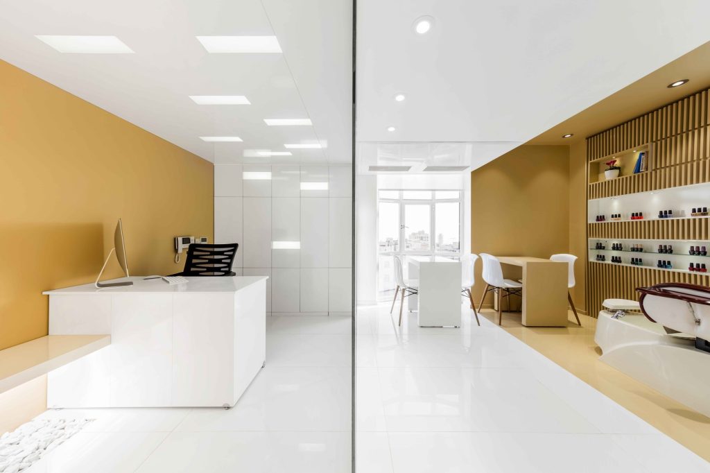 Reception and nail bar, with product shelves on a wood-slat wall.