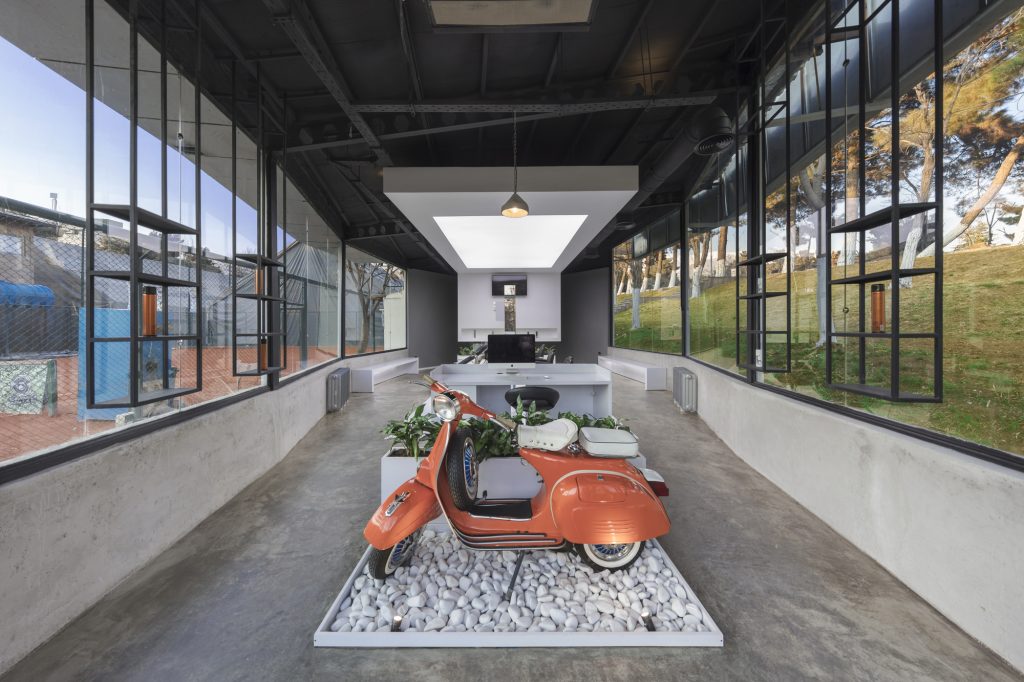 The scooter display by day, with glass walls on both sides and trees outside.