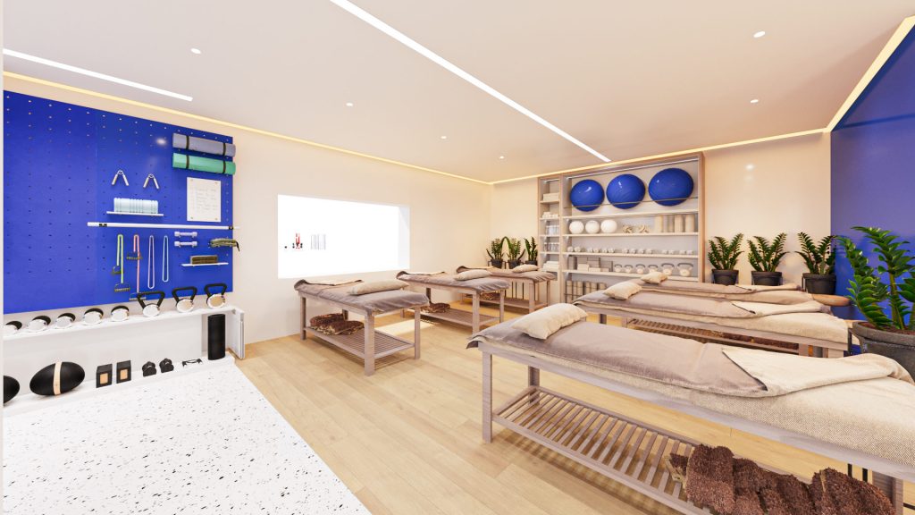 A treatment room with massage beds, a deep blue pegboard wall with equipment and shelves of exercise balls.