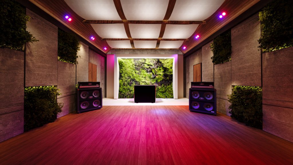 The yoga studio set up for an event, with colored lighting on the floor, speakers and a stage in front of the moss wall.
